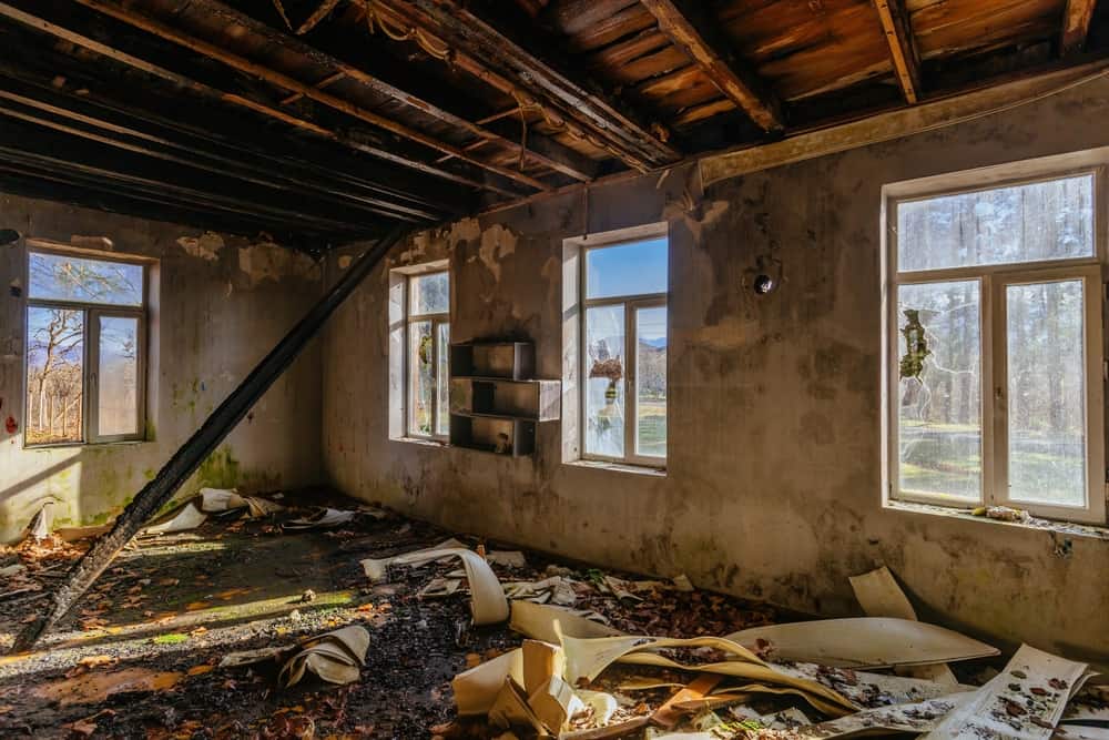 Interior area with windows, showing soot-covered walls and fire-damaged window frames, indicative of fire restoration damage.