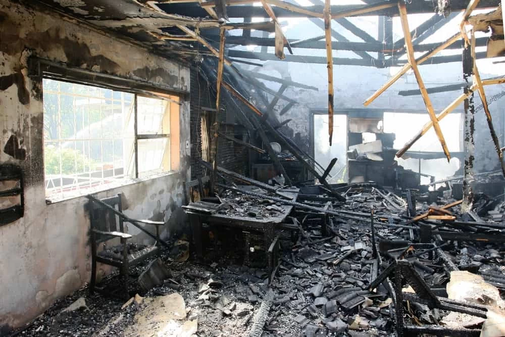 Ceiling of a house visibly falling apart due to fire damage, highlighting the urgent need for restoration.