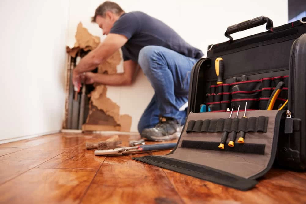 Man repairing water damage, addressing the aftermath of a water-related incident as part of the restoration process.